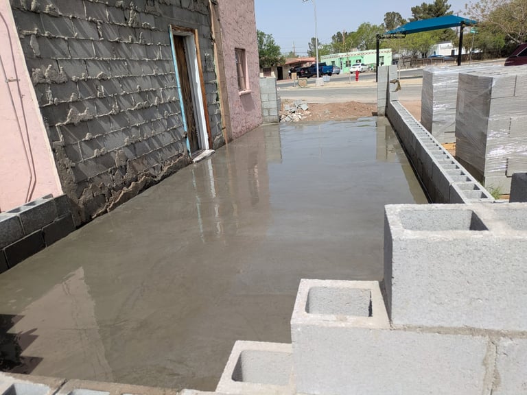 Flooded construction site with concrete blocks, pink building, and stagnant water covering the ground