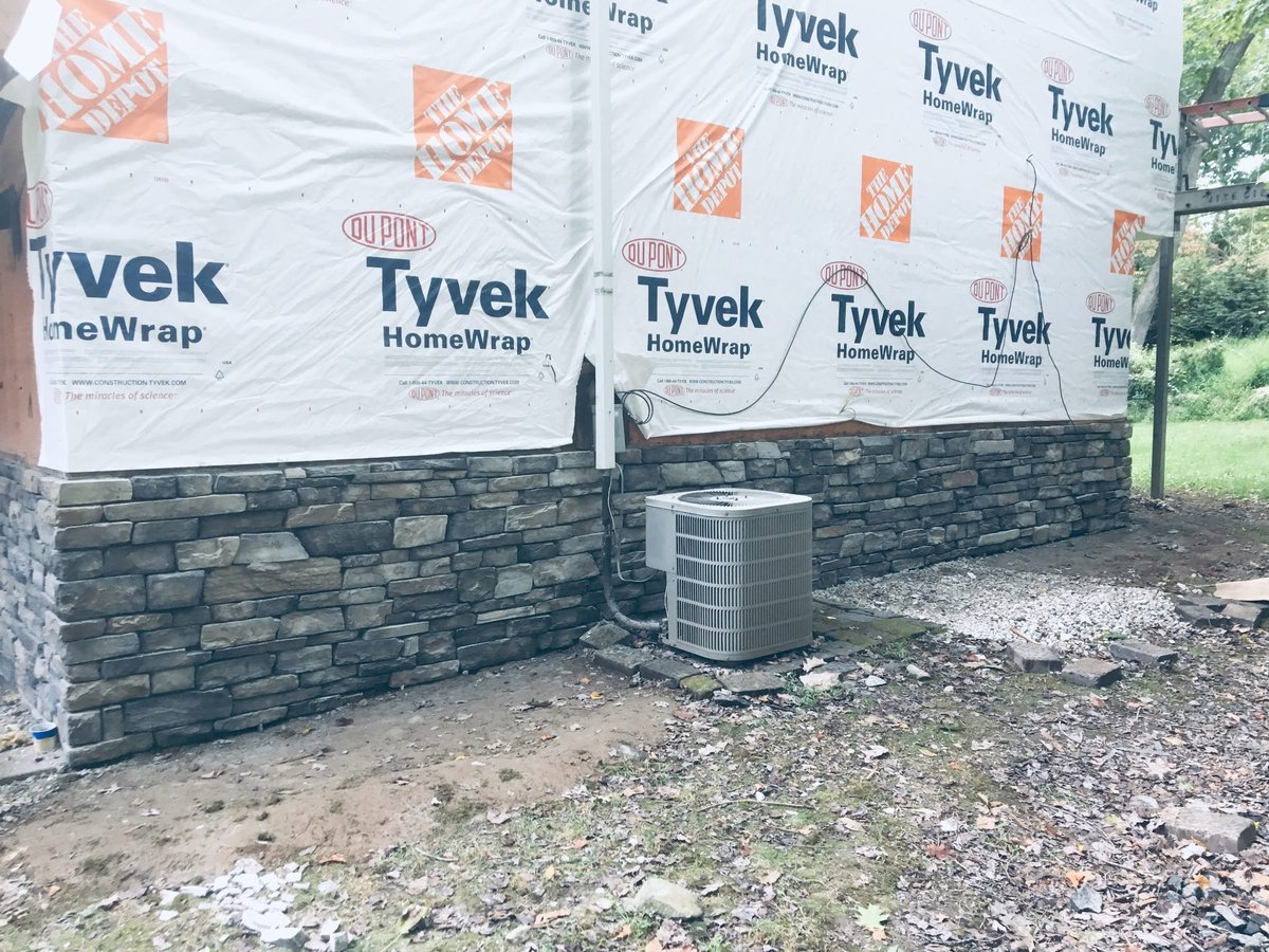 Construction site with Tyvek HomeWrap covering building exterior and Home Depot logos visible on white weather barrier